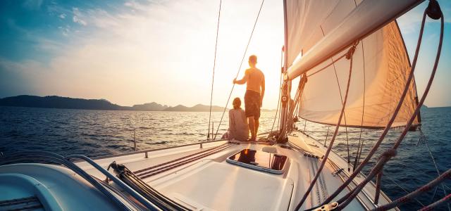 Couple enjoying sunset from the deck of the sailing boat moving in a sea
